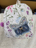 Large backpack made from quilt, has butterfly on the front, two zipper pockets in the back and one pocket on the inside with the key ring
