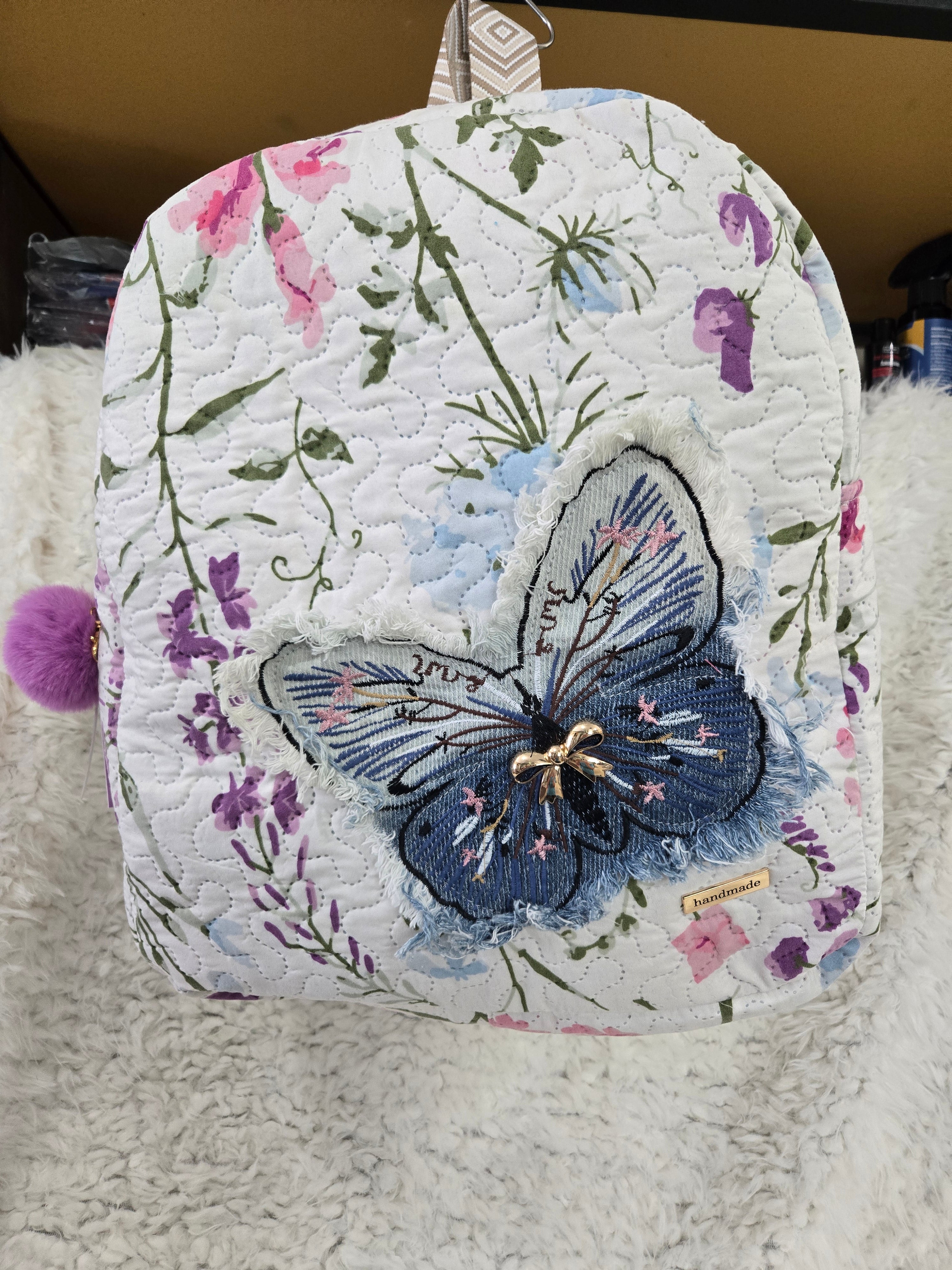 Large backpack made from quilt, has butterfly on the front, two zipper pockets in the back and one pocket on the inside with the key ring